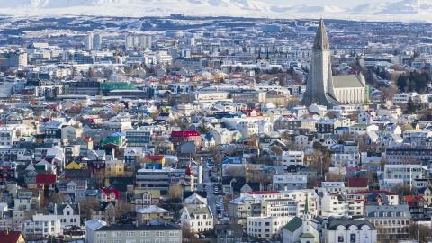 Loftmynd af Reykjavík að vetri til. Snjór, hvít fjöll í bakgrunni, Hallgrímskirkja hægra megin í rammanum fyrir miðju, Tjörnin fremst.
