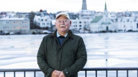 Einar D. G. Gunnlaugsson portrett. Stendur á útsýnispallinum við Tjörnina með tjörn, Fríkirkju og Hallgrímskirkju í baksýn. Vetur, klaki.