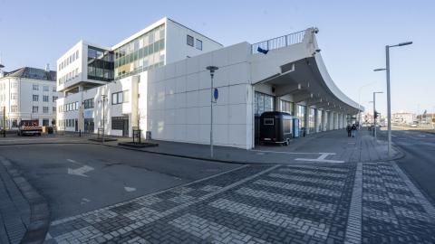 Tryggvagata 19 (Kolaportið). Myndað á ská frá Hafnartorgi sirka. Blár himinn, gatan í forgrunni.