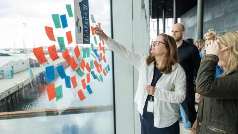 Kona setur post-it miða á glugga í Hörpu en þannig var hugmyndum safnað saman vegna nýrrar aðgerðaáætlunar velferðarstefnu Reykjavíkurborgar