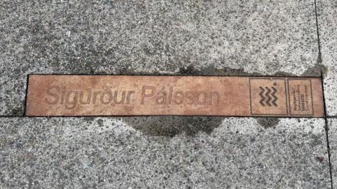 Bronze-colored sign in sidewalk with the name of author Sigurður Pálsson. Part of the literary installation at the Customs House.
