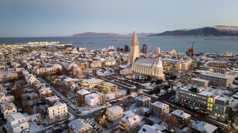 Loftmynd yfir miðborgina, Hallgrímskirkja áberandi fyrir miðju, Faxaflói og fjöllin í fjarska. Heiðskýrt, vetrarbirta.