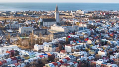 Loftmynd yfir miðborgina, Hallgrímskirkja áberandi fyrir miðri mynd. Háskólinn og sjór í fjarska. Hlutlaust veður, bjart.