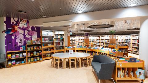 The Reykjavík City Library at Kringlan. A wide interior shot of the library features a central round table and walls lined with bookshelves. This is likely the children's section.