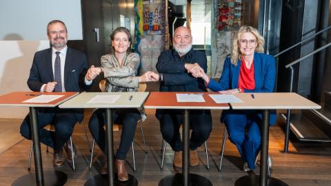 Four individuals joining hands over a desk