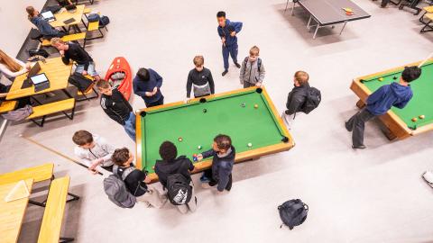 Viewed from above, students play pool on a green table during recess at Ölduselsskóli.